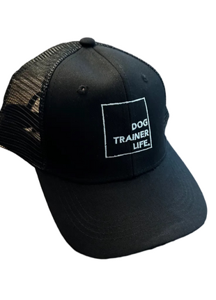 Black cap with 'Dog Trainer Life' text on a wooden floor